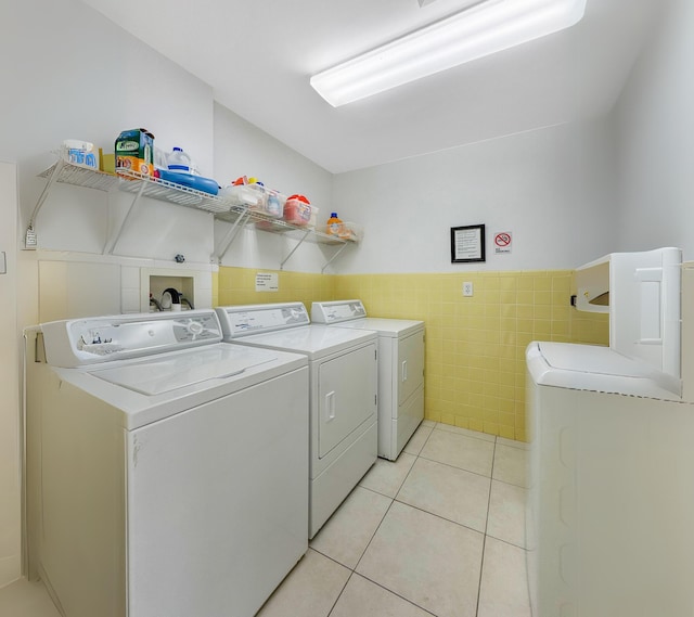 350 Beach Rd Unit 503, Tequesta, FL 33469 - laundry area with washing machine and dryer, tile walls, light tile patterned floors, and wainscoting