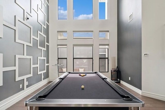 game room with wood finished floors, pool table, baseboards, a towering ceiling, and plenty of natural light