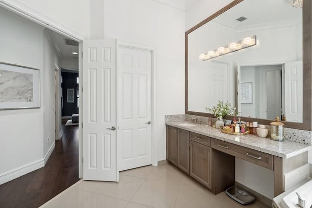bathroom featuring vanity, crown molding, and baseboards