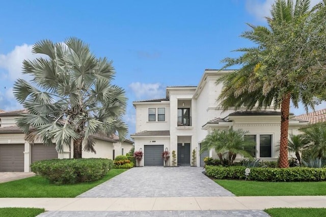 view of front of house featuring decorative driveway, a garage, stucco siding, and a front yard