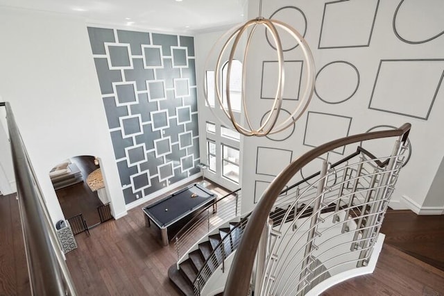 staircase featuring baseboards, wood finished floors, and an accent wall