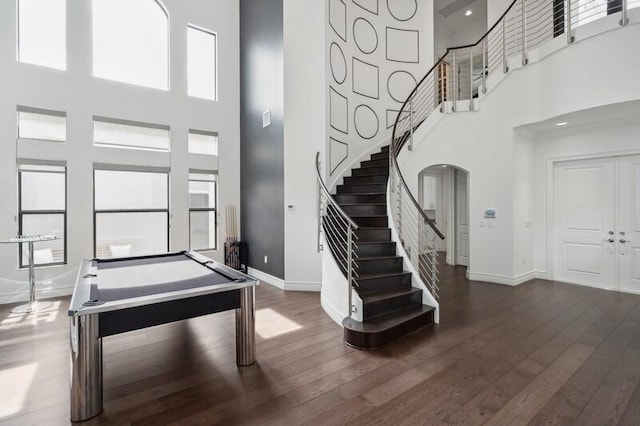 foyer entrance with a high ceiling, baseboards, stairway, plenty of natural light, and dark wood finished floors