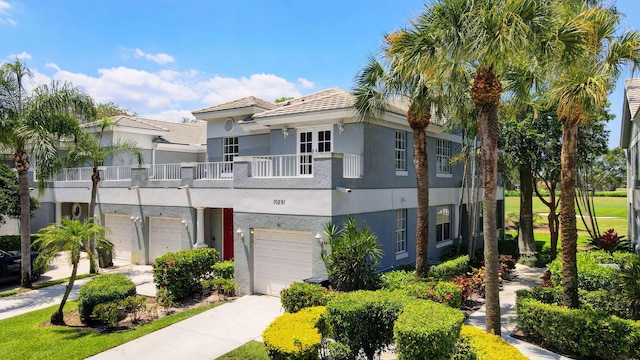 view of front of home featuring stucco siding, concrete driveway, a garage, and a balcony