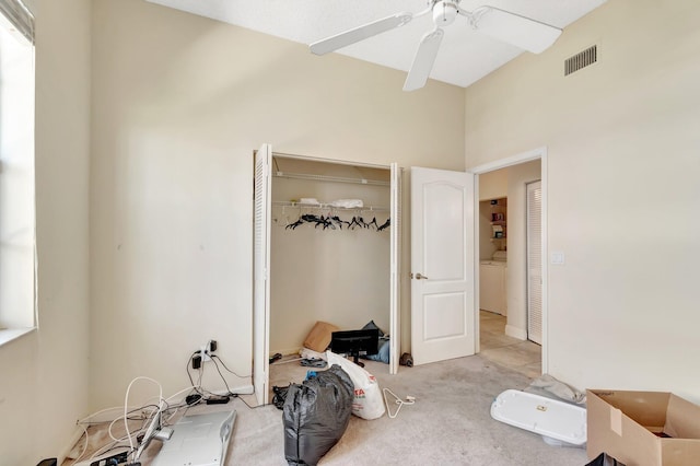 unfurnished bedroom featuring a closet, light carpet, washer / dryer, and ceiling fan