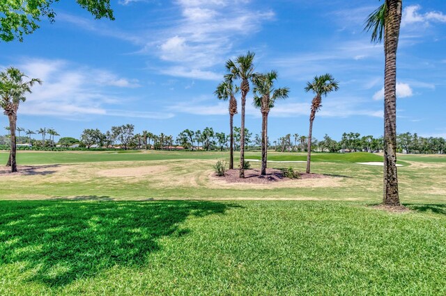 view of community featuring view of golf course and a yard