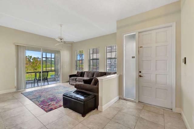 living area featuring a ceiling fan, baseboards, and light tile patterned floors