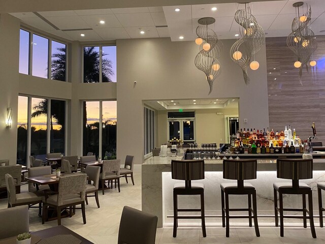 bar area featuring a high ceiling, hanging light fixtures, and recessed lighting