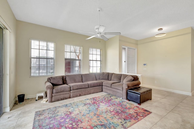 living area featuring ceiling fan, light tile patterned floors, and baseboards