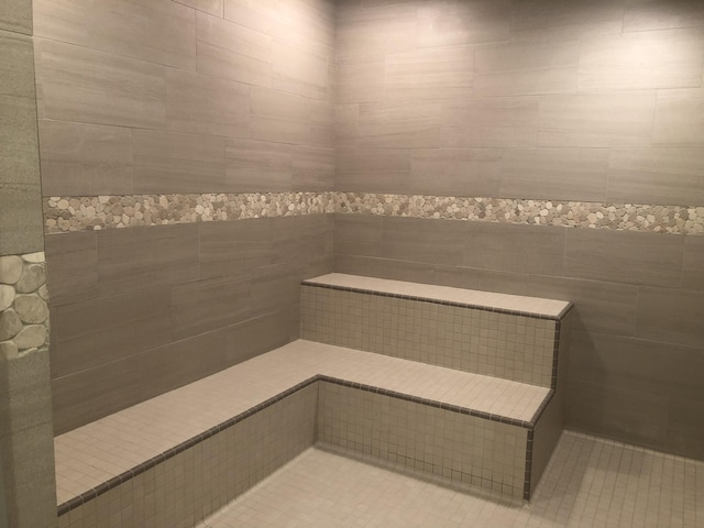 full bathroom with tile patterned floors, a tile shower, a sauna, and tile walls