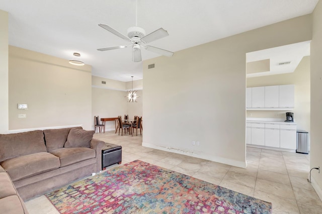 living room featuring ceiling fan, a chandelier, light tile patterned floors, and baseboards