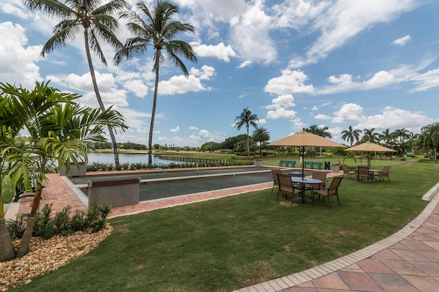 view of home's community featuring a bocce ball area, a water view, and a lawn