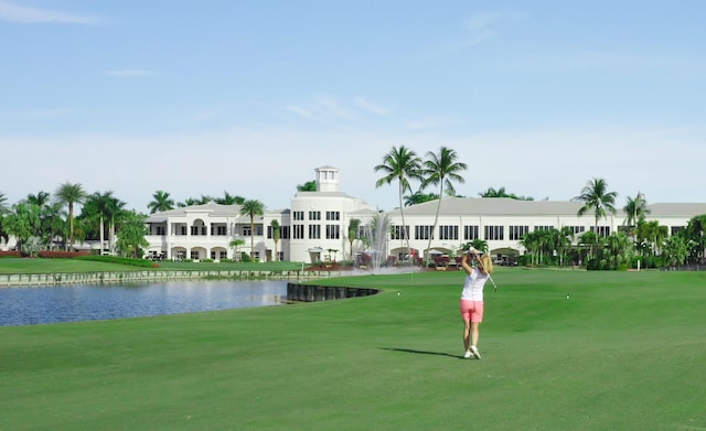 view of property's community with a water view, a yard, and view of golf course
