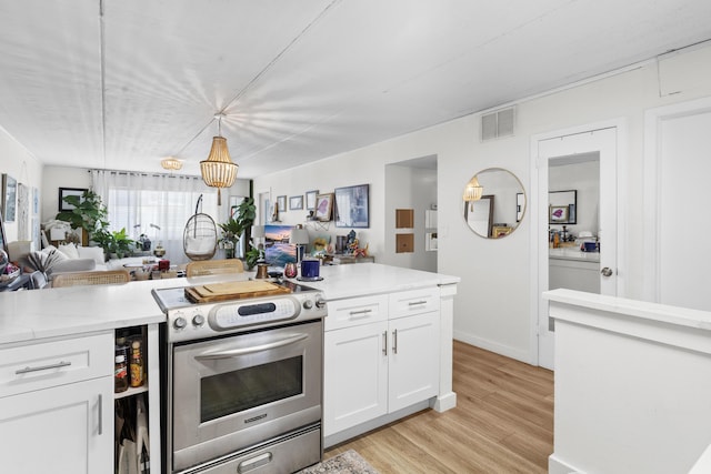 kitchen featuring electric stove, open floor plan, white cabinetry, light wood-style floors, and pendant lighting