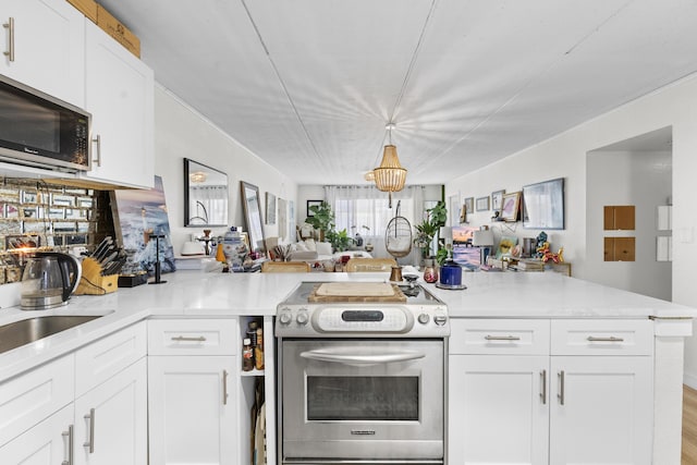 kitchen featuring appliances with stainless steel finishes, open floor plan, white cabinets, and a peninsula