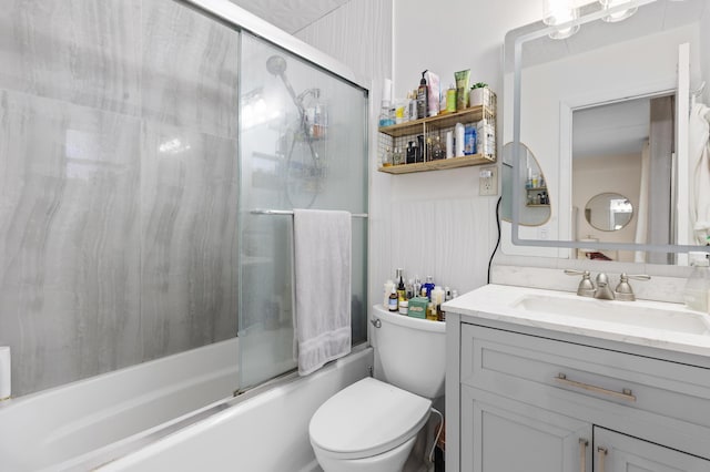 full bath with vanity, bath / shower combo with glass door, toilet, and a wainscoted wall