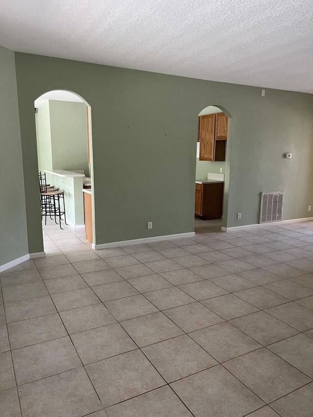 6110 46th Ln, Vero Beach, FL 32967 - spare room with arched walkways, light tile patterned flooring, a textured ceiling, and baseboards