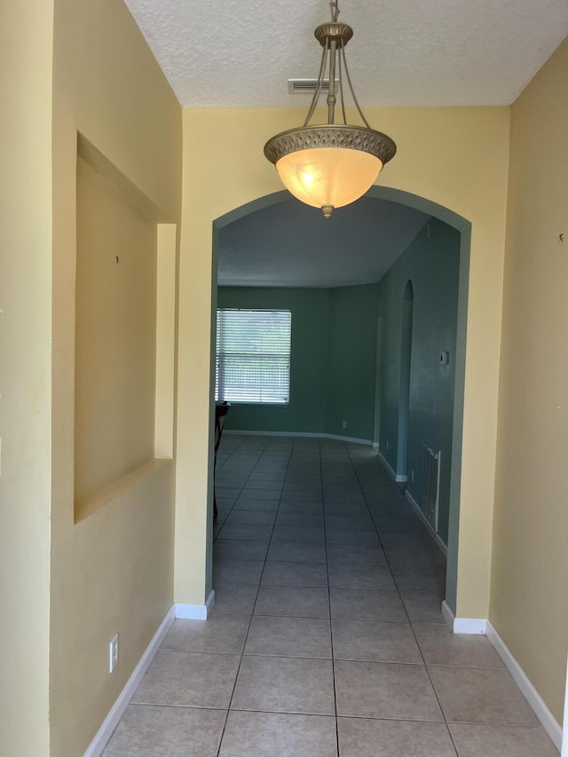 6110 46th Ln, Vero Beach, FL 32967 - hall featuring arched walkways, a textured ceiling, light tile patterned floors, and baseboards
