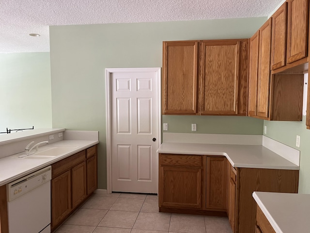 6110 46th Ln, Vero Beach, FL 32967 - kitchen featuring dishwasher, a sink, brown cabinetry, a textured ceiling, and light tile patterned flooring