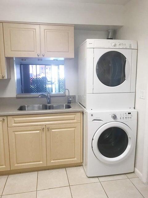 2050 Oleander Blvd Unit 1-105, Fort Pierce, FL 34950 - washroom with estacked washer and dryer, light tile patterned floors, and cabinet space