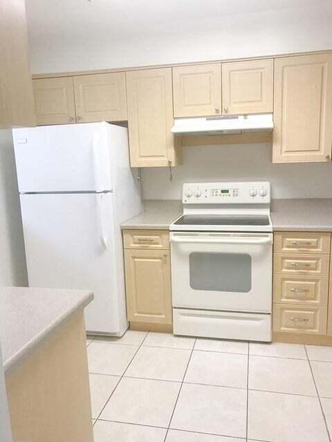 2050 Oleander Blvd Unit 1-105, Fort Pierce, FL 34950 - kitchen featuring white appliances, under cabinet range hood, light countertops, and light brown cabinetry