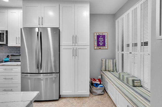 730 Greensward Ct Unit 107-J, Delray Beach, FL 33445 - kitchen with appliances with stainless steel finishes, white cabinetry, light stone counters, light tile patterned flooring, and decorative backsplash