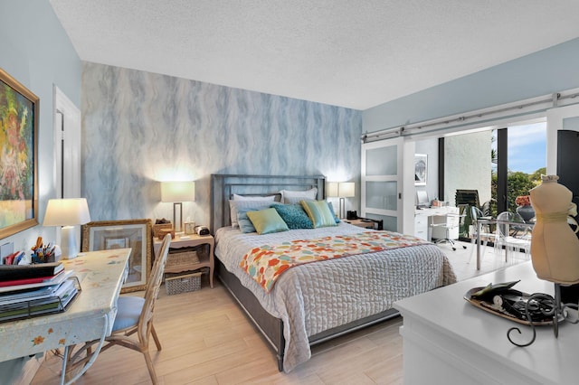 730 Greensward Ct Unit 107-J, Delray Beach, FL 33445 - bedroom with an accent wall, access to outside, light wood finished floors, and a textured ceiling