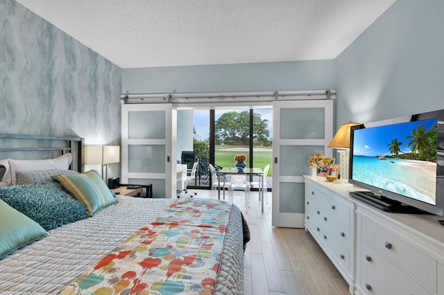 730 Greensward Ct Unit 107-J, Delray Beach, FL 33445 - bedroom with access to outside, a textured ceiling, and light wood-style flooring