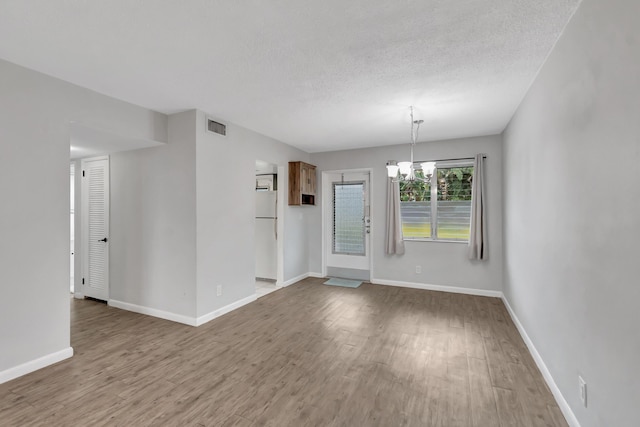 2161 NE 42nd Ct Unit 116, Lighthouse Point, FL 33064 - spare room with a chandelier, wood finished floors, baseboards, and a textured ceiling