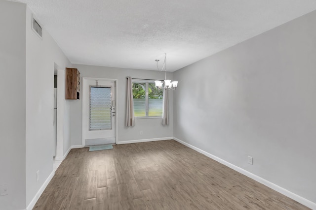 2161 NE 42nd Ct Unit 116, Lighthouse Point, FL 33064 - unfurnished dining area featuring a chandelier, wood finished floors, a textured ceiling, and baseboards