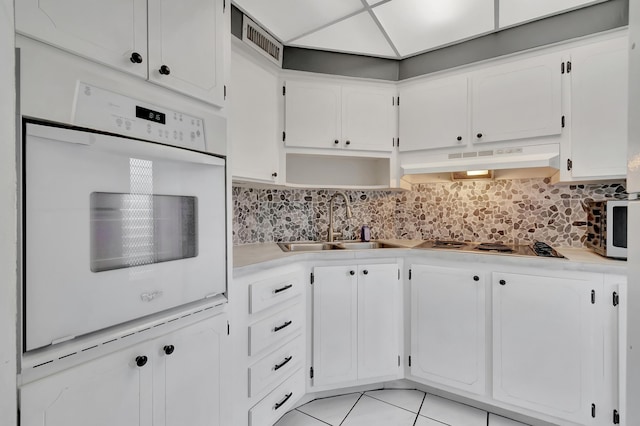 2161 NE 42nd Ct Unit 116, Lighthouse Point, FL 33064 - kitchen with under cabinet range hood, white oven, a sink, stainless steel cooktop, and light countertops