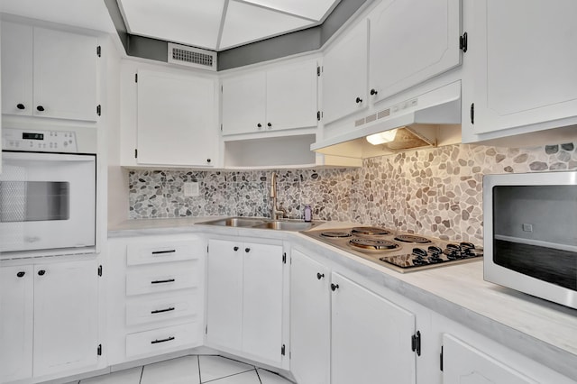 2161 NE 42nd Ct Unit 116, Lighthouse Point, FL 33064 - kitchen with white appliances, a sink, under cabinet range hood, light countertops, and decorative backsplash