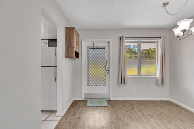 2161 NE 42nd Ct Unit 116, Lighthouse Point, FL 33064 - doorway featuring a chandelier, baseboards, and light wood-style flooring