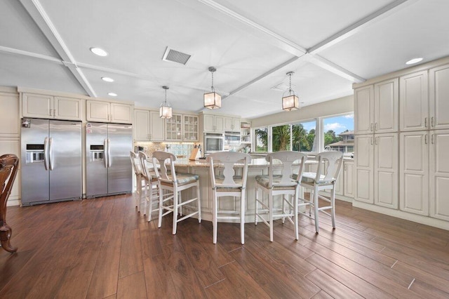16 E High Point Rd, Sewalls Point, FL 34996 - kitchen with appliances with stainless steel finishes, recessed lighting, glass insert cabinets, dark wood finished floors, and a breakfast bar area