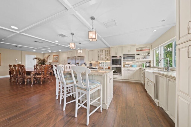 16 E High Point Rd, Sewalls Point, FL 34996 - kitchen featuring stainless steel appliances, dark wood-style floors, light stone countertops, a kitchen bar, and open shelves