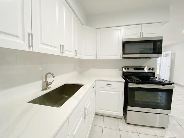 2715 Ponce De Leon Blvd, Delray Beach, FL 33445 - kitchen with stainless steel appliances, a sink, light tile patterned floors, white cabinets, and light countertops