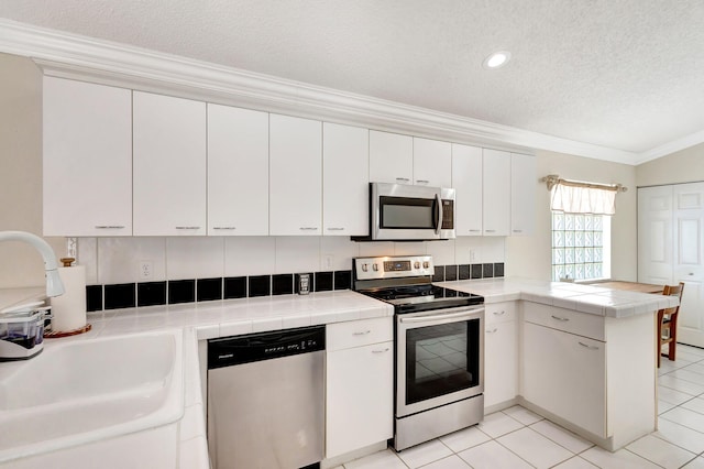 1833 Barnstable Rd, Wellington, FL 33414 - kitchen with appliances with stainless steel finishes, a peninsula, crown molding, a textured ceiling, and a sink