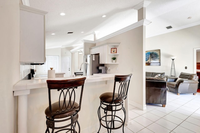 1833 Barnstable Rd, Wellington, FL 33414 - kitchen with freestanding refrigerator, tile countertops, ornamental molding, a peninsula, and a breakfast bar area