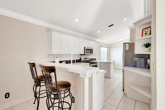 1833 Barnstable Rd, Wellington, FL 33414 - kitchen featuring open shelves, stainless steel appliances, a peninsula, tile counters, and ornamental molding