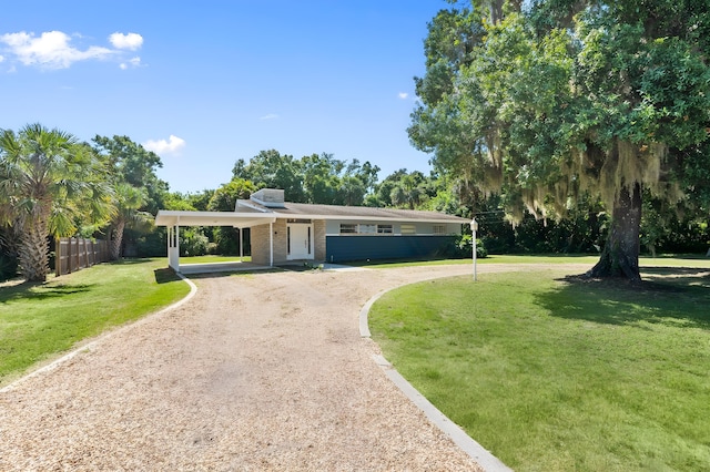 2560 50th Ave, Vero Beach, FL 32966 - view of front of house with driveway, an attached carport, brick siding, and view of scattered trees
