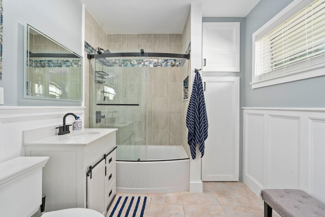2560 50th Ave, Vero Beach, FL 32966 - full bath with toilet, bath / shower combo with glass door, vanity, tile patterned floors, and wainscoting