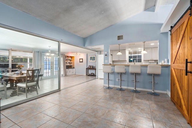 2560 50th Ave, Vero Beach, FL 32966 - kitchen with a barn door, lofted ceiling, a breakfast bar area, white cabinetry, and pendant lighting