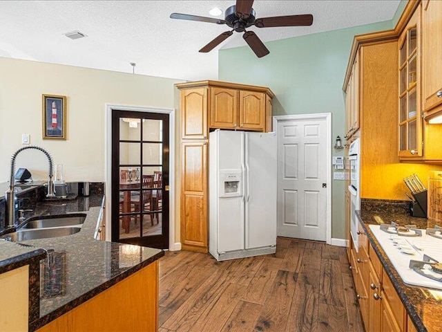 6575 NW Pomona Ct, Port Saint Lucie, FL 34983 - kitchen with white appliances, dark wood finished floors, a ceiling fan, glass insert cabinets, and dark stone countertops