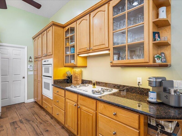 6575 NW Pomona Ct, Port Saint Lucie, FL 34983 - kitchen with white appliances, dark wood-style flooring, dark stone countertops, a ceiling fan, and glass insert cabinets