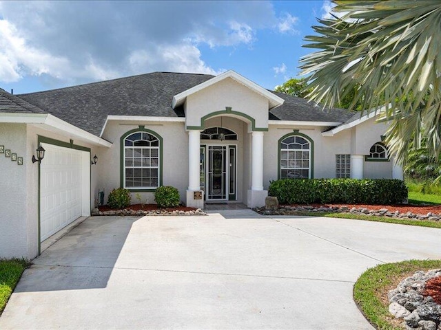 6575 NW Pomona Ct, Port Saint Lucie, FL 34983 - view of exterior entry with a garage, concrete driveway, stucco siding, and a shingled roof