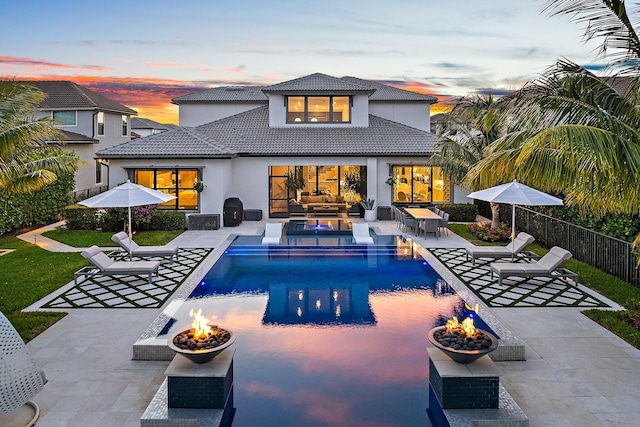 122 Cerulean Key Way, Jupiter, FL 33478 - back of house at dusk with stucco siding, a tile roof, a patio area, and an outdoor living space with a fire pit