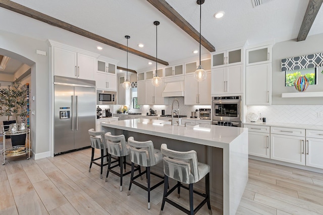 122 Cerulean Key Way, Jupiter, FL 33478 - kitchen with built in appliances, beam ceiling, custom range hood, arched walkways, and decorative backsplash