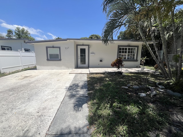 711 Fernwood Dr, West Palm Beach, FL 33405 - ranch-style house with stucco siding, fence, a patio, and concrete driveway