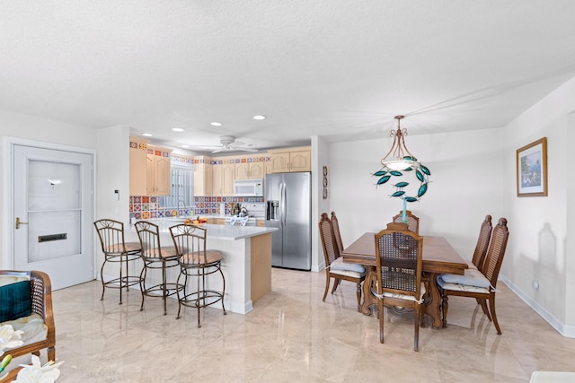 201 Bayview Ave Unit D, Boynton Beach, FL 33435 - kitchen featuring stainless steel refrigerator with ice dispenser, white microwave, a peninsula, light brown cabinetry, and a breakfast bar area