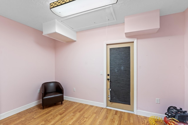 unfurnished room with attic access, wood finished floors, and baseboards