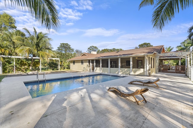 swimming pool with a sunroom and a patio area